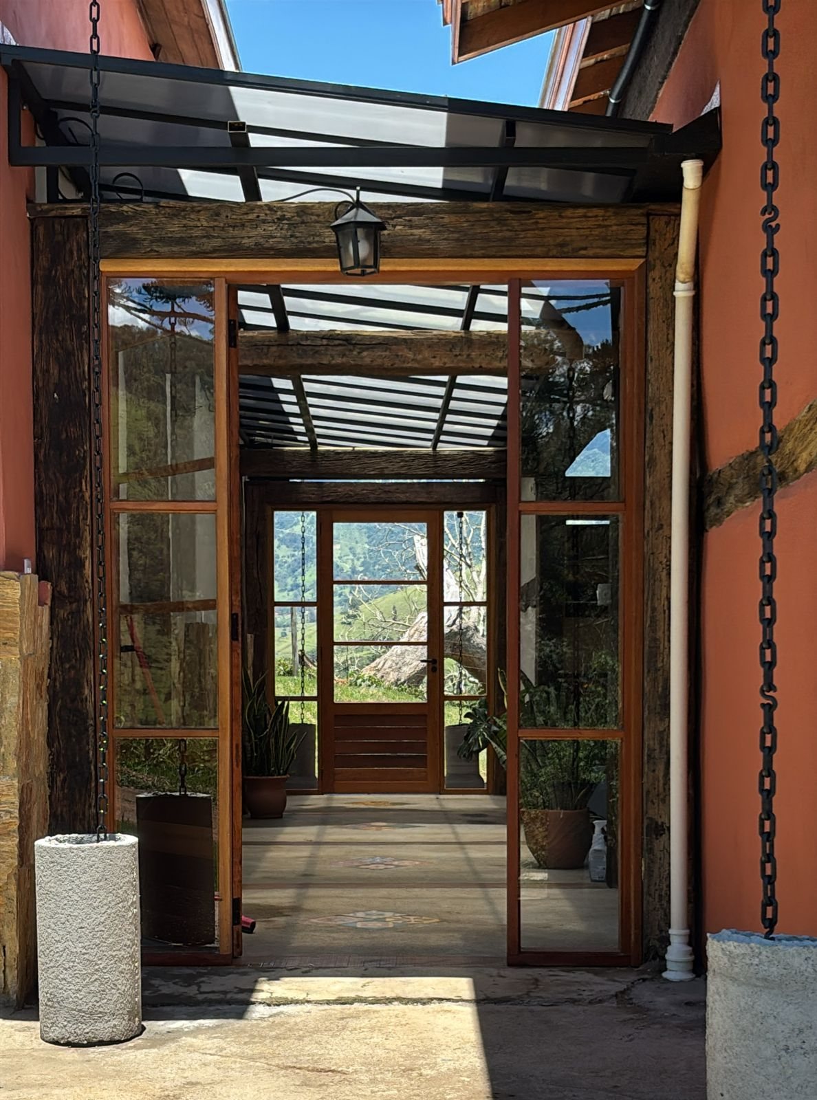 Entrada de vidro e madeira da Morada, aberta para a paisagem
