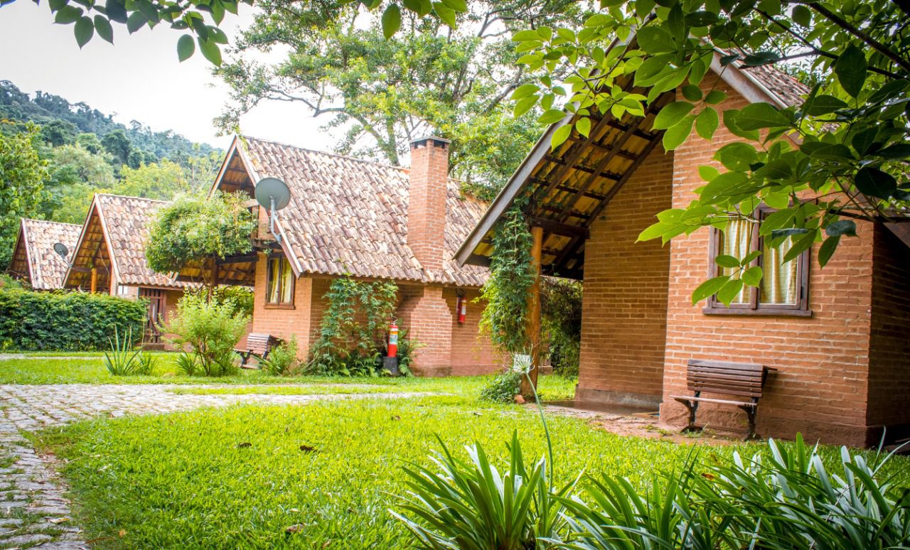 Chalés de tijolo entre o jardim e as árvores da Mantiqueira