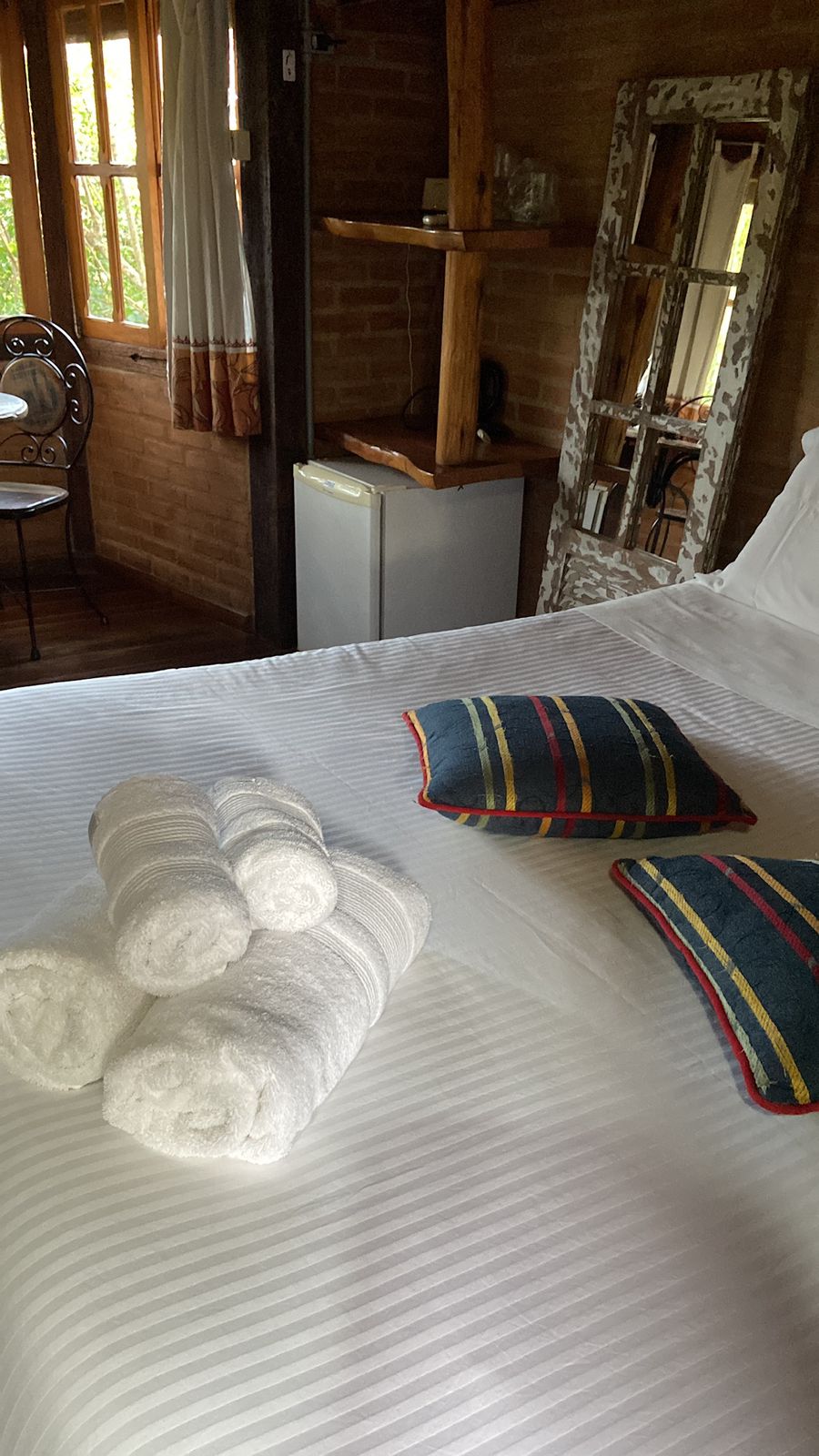Toalhas enroladas e almofadas listradas sobre a cama